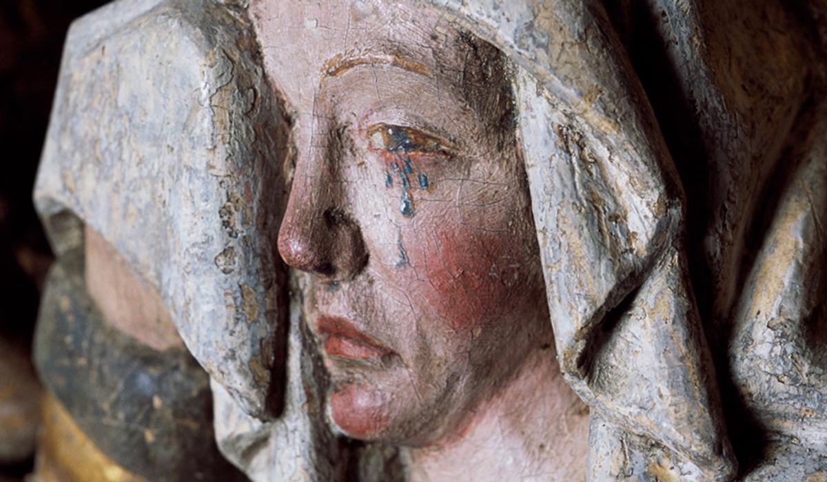 Bemålad träskulptur av en gråtande madonna.
