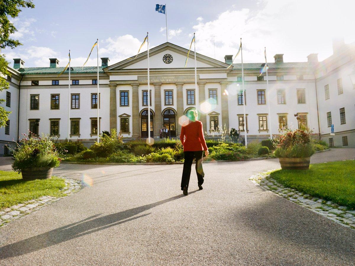 Foto på Landstingshuset i Region Stockholm. Framför huset går en kvinna.